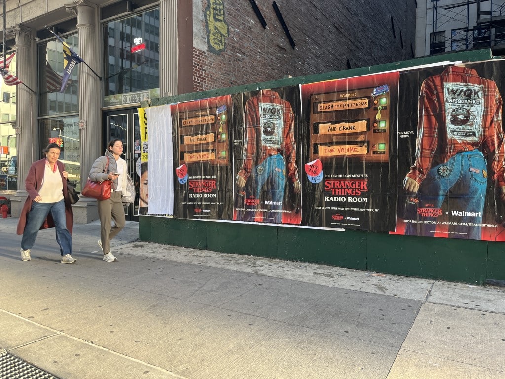 Wild Posting® display in Tribeca, NYC featuring Stranger Things × Walmart posters on a construction barricade.