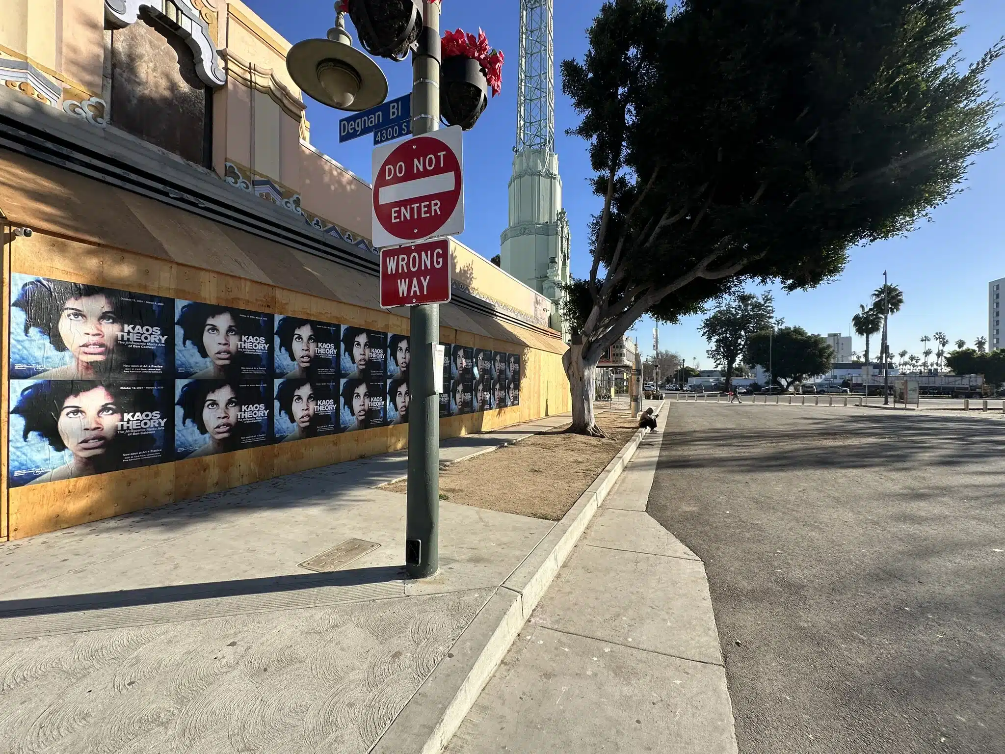 Urban Flyposting on Degnan Boulevard Featuring "Kaos Theory" 🌟 WILD POSTING® A series of "Kaos Theory" posters displayed on a boarded-up building along Degnan Boulevard, with a "Do Not Enter" sign and tree-lined street in the background.