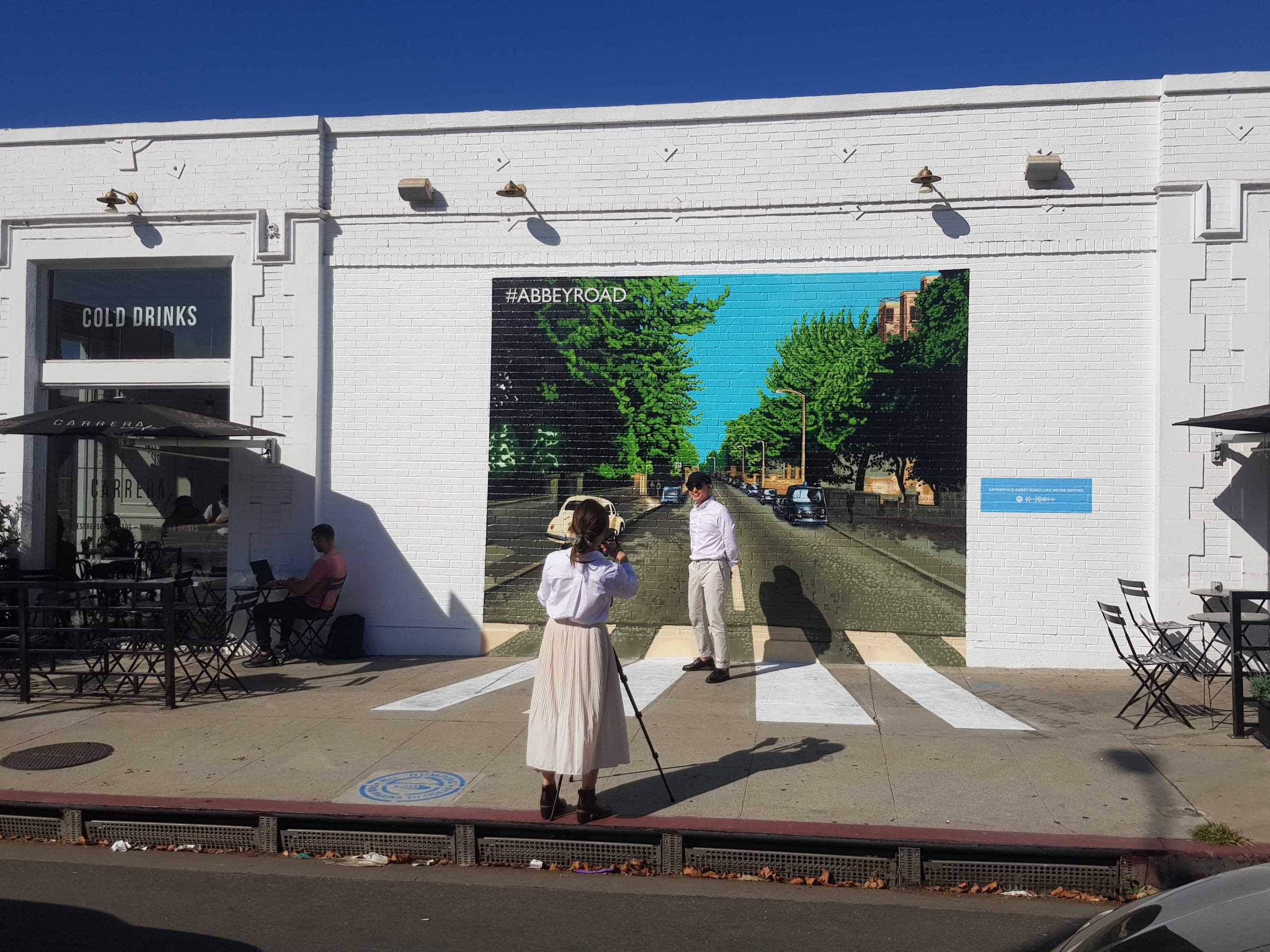 People posing in front of a Beatles Abbey Road mural on Melrose Avenue in Los Angeles, recreating the iconic crosswalk album cover.