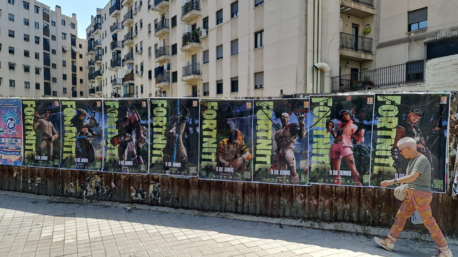 Wild Posting® Fortnite campaign featuring a full wall of repeated posters installed along a residential street in Madrid.