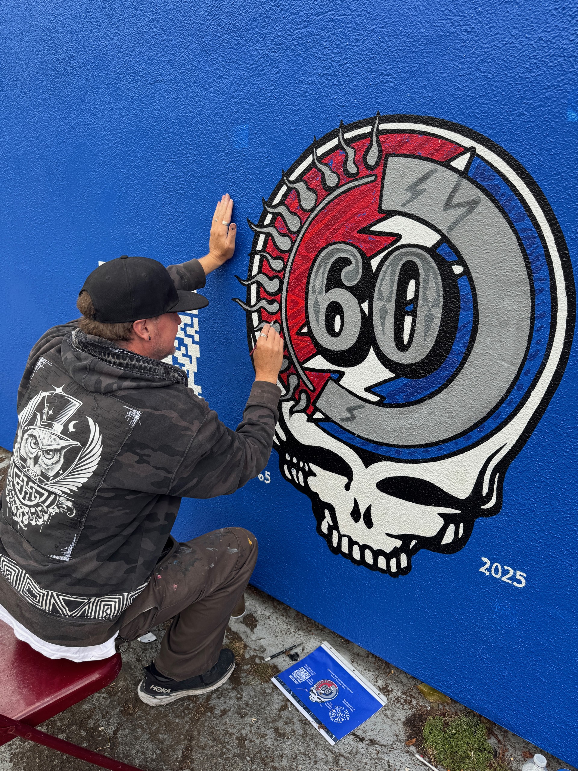 Artist hand-painting a Grateful Dead 60th anniversary skull mural in San Francisco, celebrating the band’s legacy with a bold street art installation.