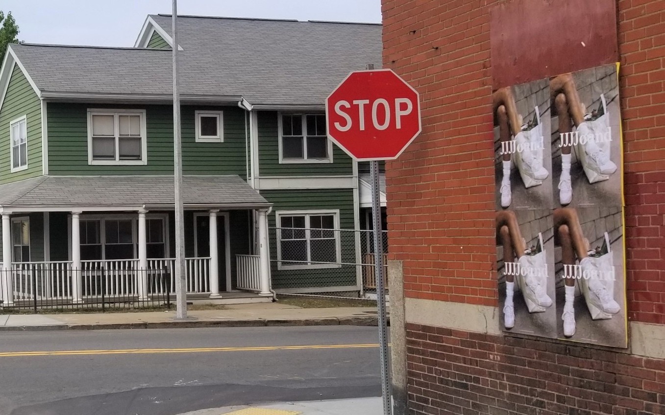 JJJJound Wild Posting® campaign on boarded storefront wall in Boston