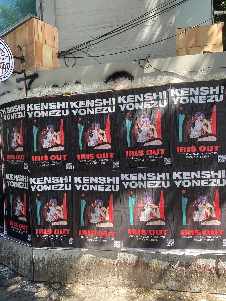 Wild Posting® campaign featuring repeated Kenshi Yonezu “IRIS OUT” posters covering a full urban street wall for high-impact visibility.