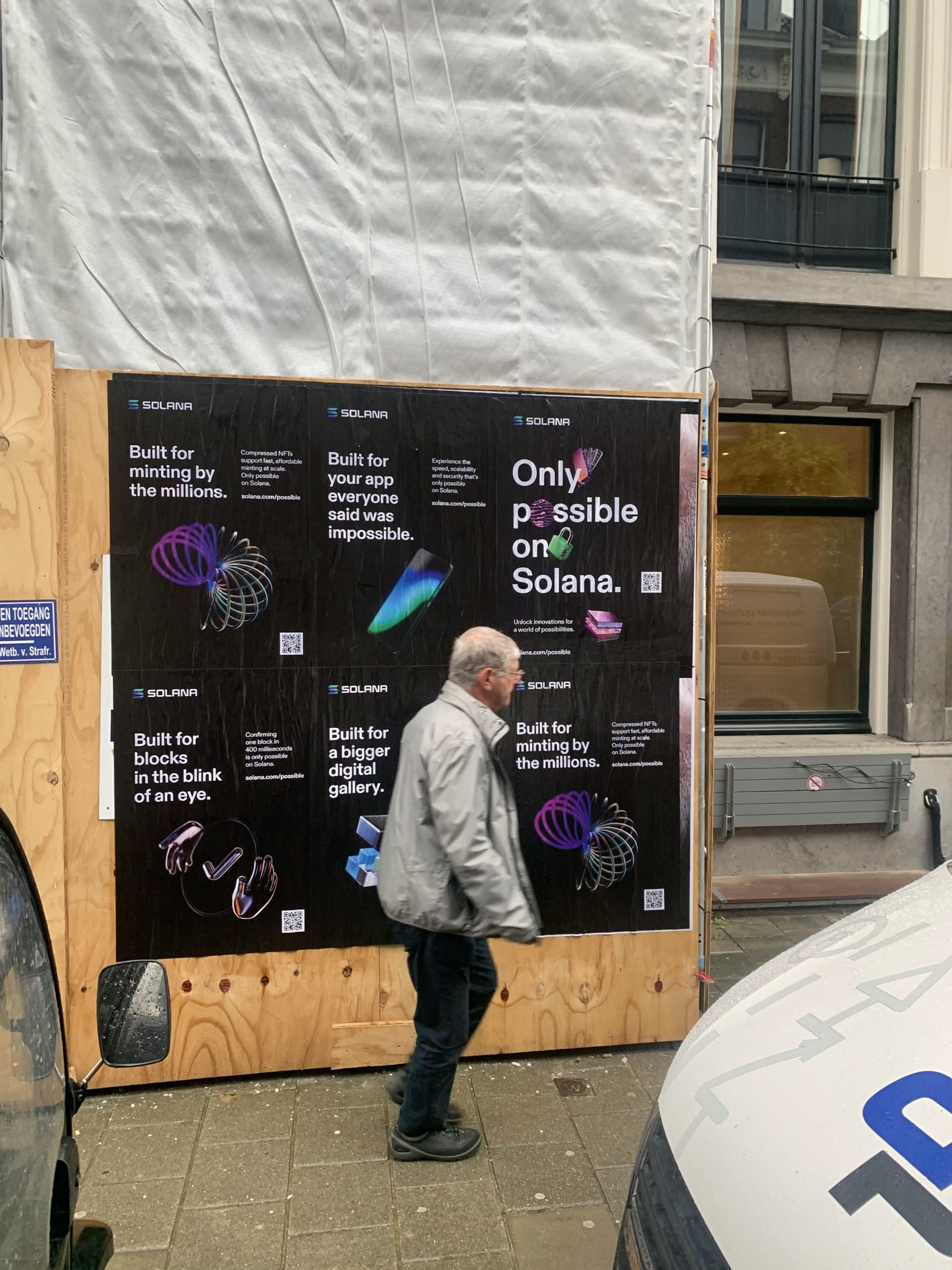 Solana Wild Posting® street advertising campaign installed on a construction wall in Amsterdam, featuring multiple black posters promoting blockchain technology.