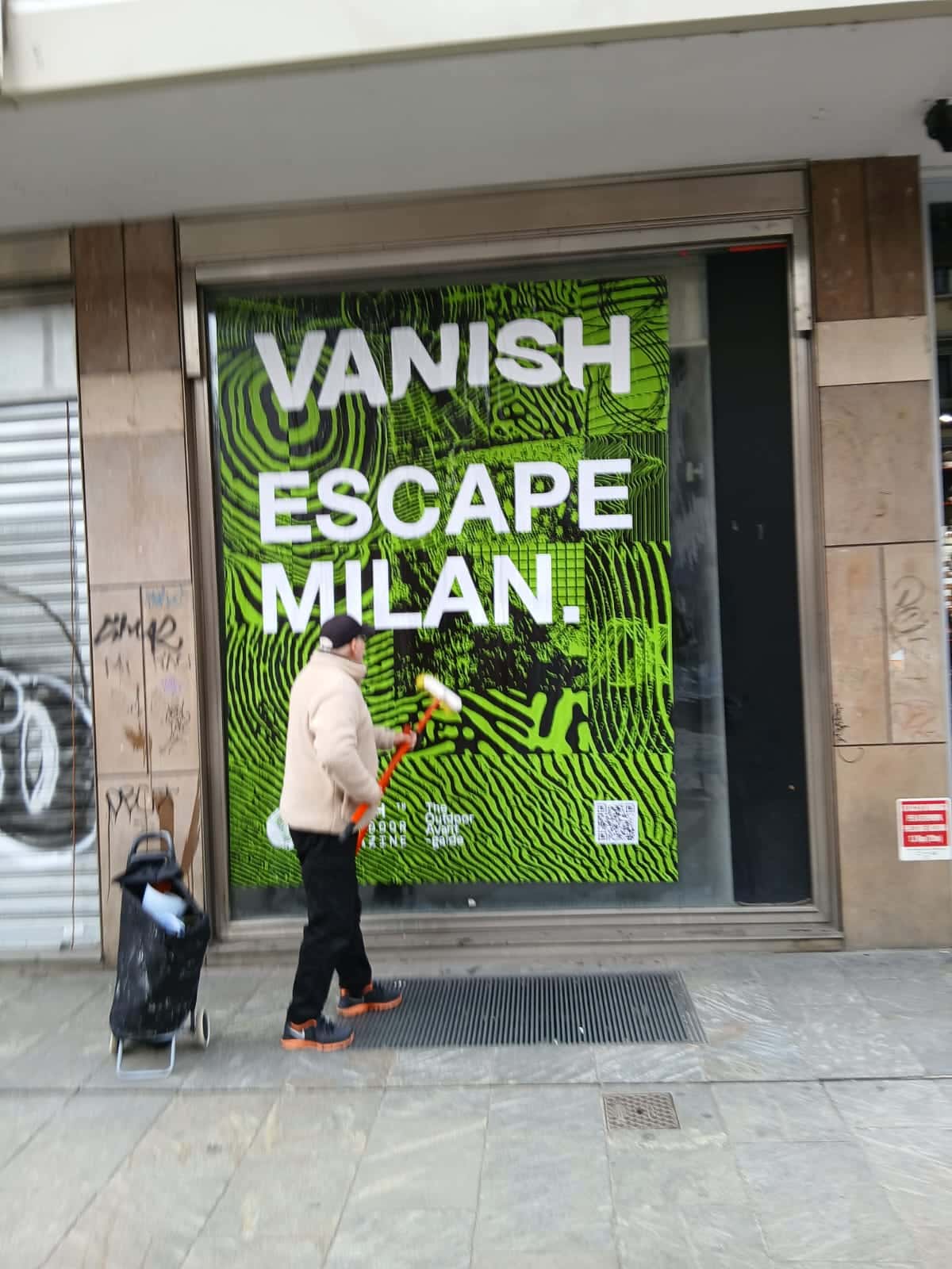 Wild Posting® storefront campaign in Milan featuring “Vanish Escape Milan” window takeover with bold green street poster installation.